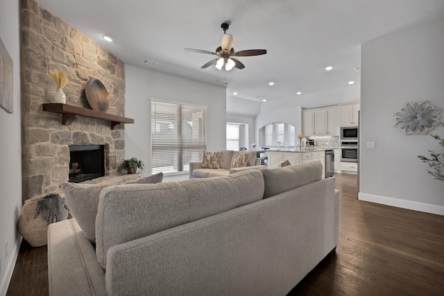 living room featuring baseboards, a stone fireplace, recessed lighting, a ceiling fan, and dark wood-style flooring