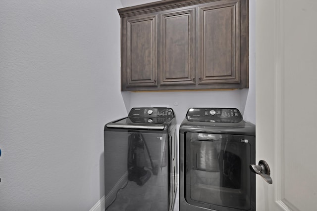 clothes washing area with washer and dryer, cabinet space, and baseboards