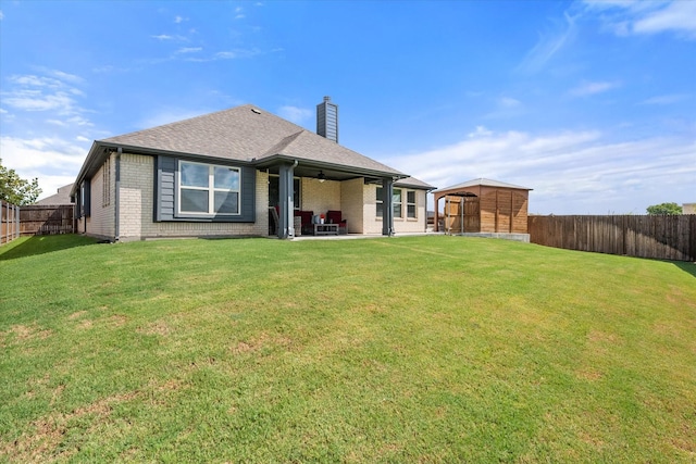 back of house featuring a yard, a patio area, a fenced backyard, and a chimney