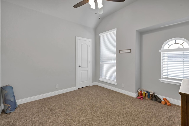 interior space with baseboards, lofted ceiling, carpet floors, and a ceiling fan