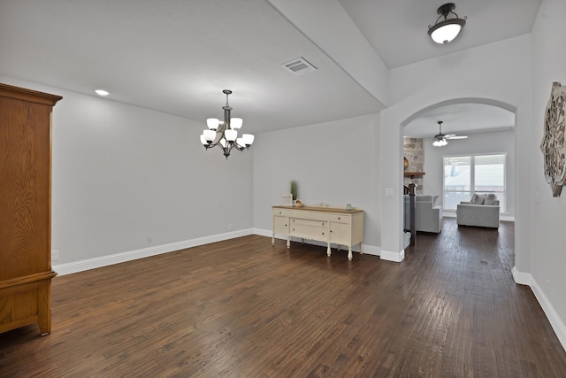 interior space featuring visible vents, ceiling fan with notable chandelier, dark wood finished floors, arched walkways, and baseboards