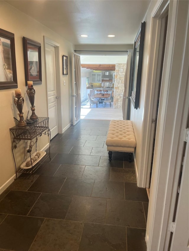 hallway with baseboards, stone tile floors, and recessed lighting
