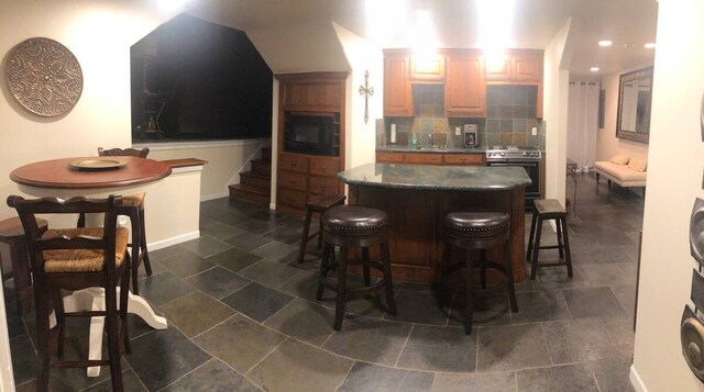bar featuring decorative backsplash, wall oven, stairway, a sink, and stainless steel range with electric cooktop