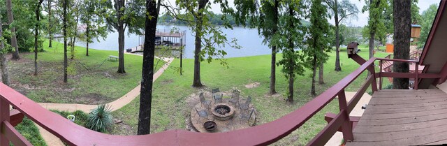 view of property's community featuring a lawn, a water view, and an outdoor fire pit