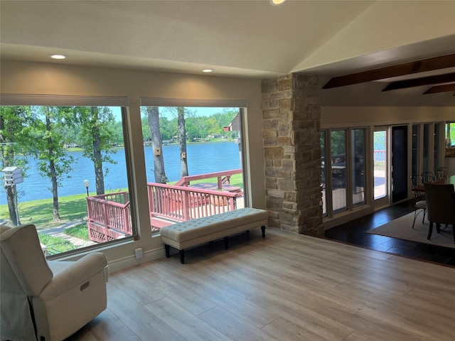 interior space with a water view, vaulted ceiling, recessed lighting, and wood finished floors