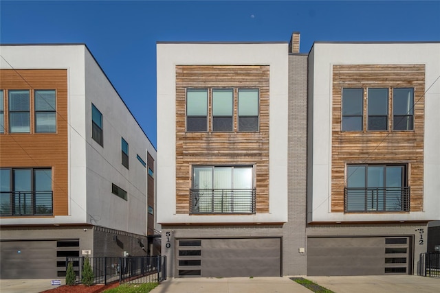 contemporary home featuring concrete driveway, an attached garage, and fence