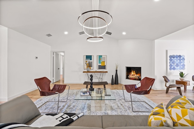 living room with wood finished floors, visible vents, lofted ceiling, recessed lighting, and a warm lit fireplace