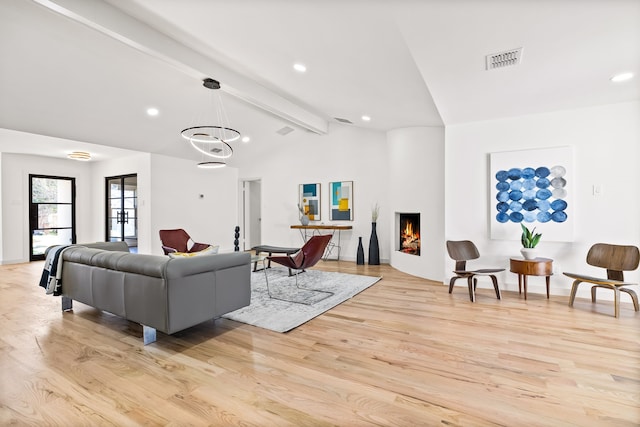 living area featuring visible vents, light wood-style flooring, lofted ceiling with beams, recessed lighting, and a lit fireplace