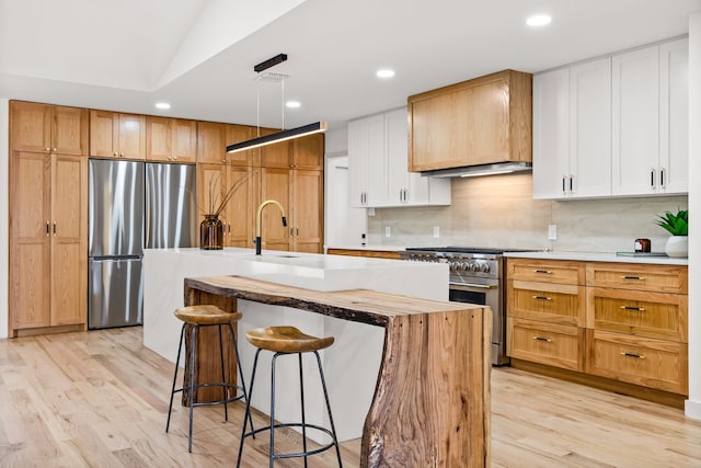 kitchen with a breakfast bar, light wood-type flooring, appliances with stainless steel finishes, and a sink