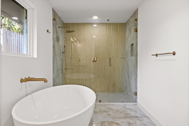 full bath featuring a shower stall, a freestanding tub, baseboards, and marble finish floor