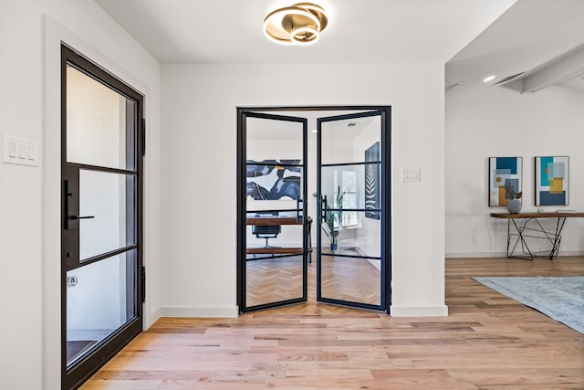 foyer entrance featuring lofted ceiling with beams, baseboards, and wood finished floors