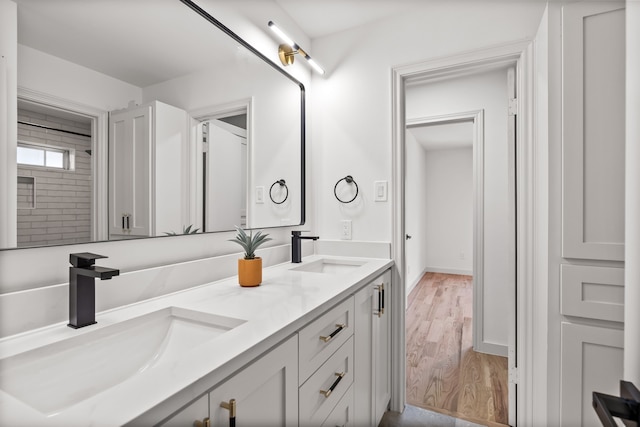 bathroom featuring double vanity, wood finished floors, and a sink