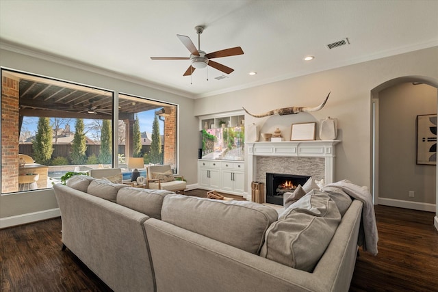 living room featuring arched walkways, visible vents, dark wood-style flooring, and a lit fireplace