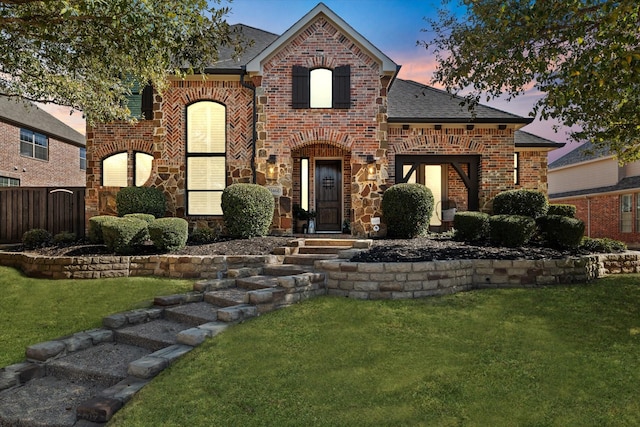 view of front of home with a front lawn, fence, brick siding, and a shingled roof