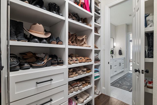 walk in closet with dark wood finished floors