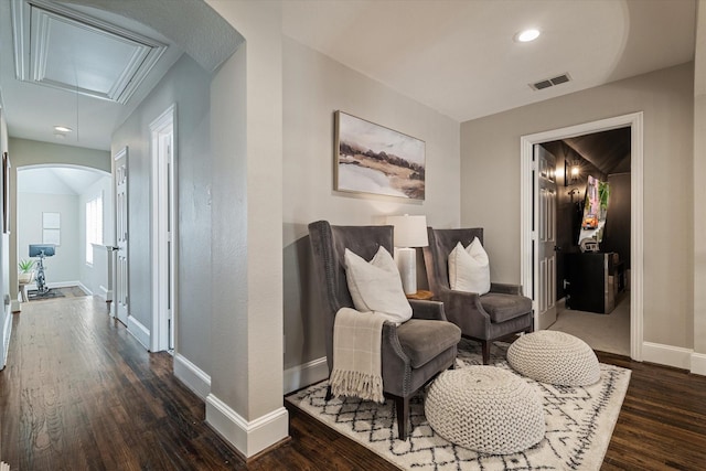 sitting room featuring visible vents, baseboards, attic access, arched walkways, and dark wood-style floors