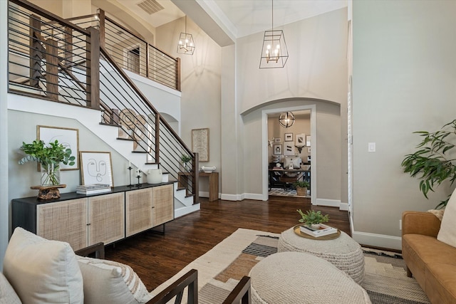 living room with visible vents, a notable chandelier, dark wood finished floors, arched walkways, and baseboards