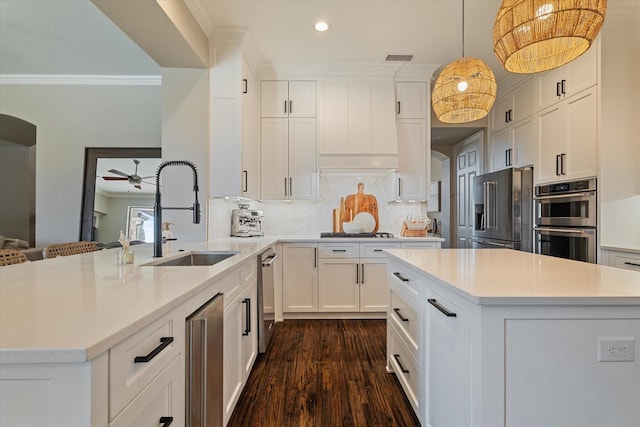 kitchen with a sink, light countertops, ornamental molding, stainless steel appliances, and dark wood-style flooring