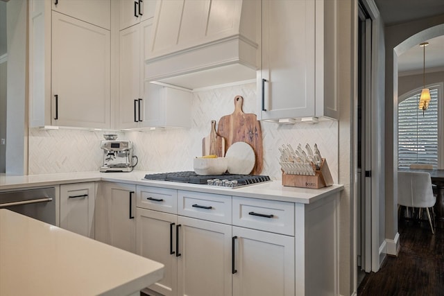 kitchen with premium range hood, arched walkways, ornamental molding, stainless steel appliances, and light countertops