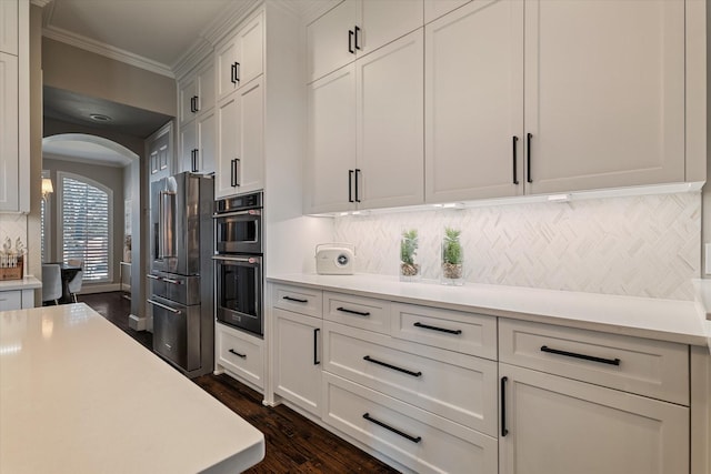 kitchen featuring ornamental molding, arched walkways, high quality fridge, double oven, and light countertops