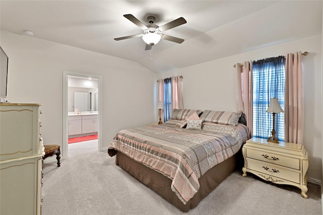 bedroom featuring light colored carpet, ensuite bath, lofted ceiling, and ceiling fan