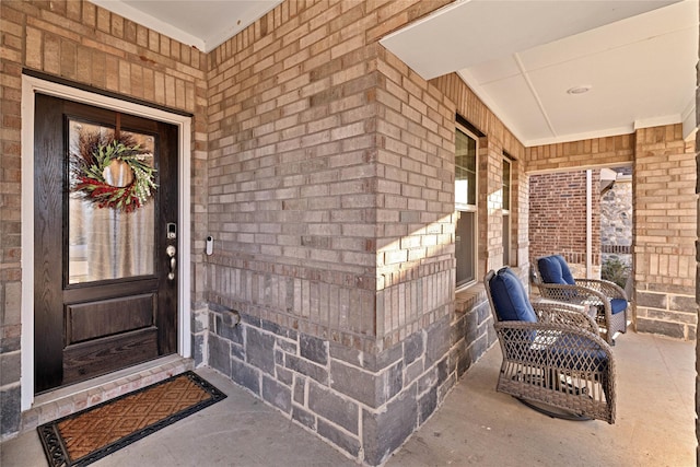 doorway to property featuring brick siding and a porch