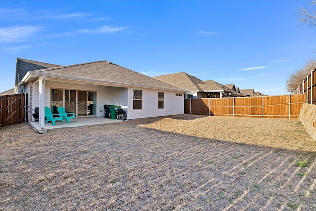 back of property with a fenced backyard, a patio, and roof with shingles