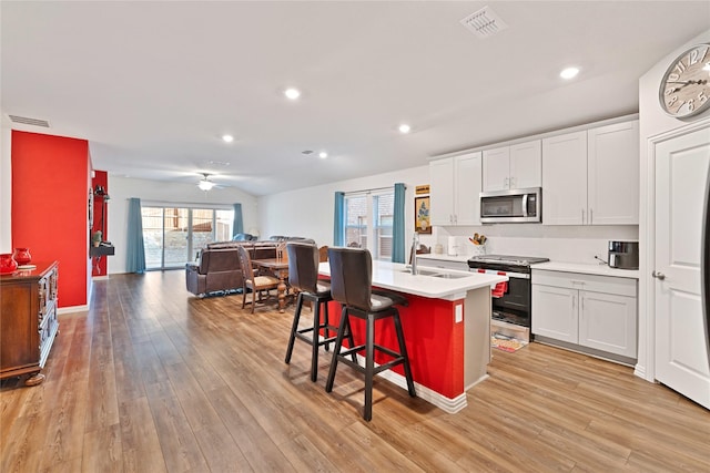 kitchen with visible vents, light wood-style flooring, a sink, open floor plan, and stainless steel appliances