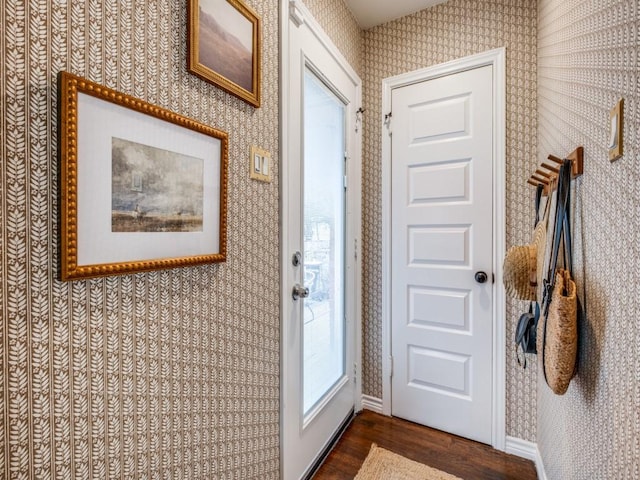 doorway to outside featuring baseboards, dark wood-style floors, and wallpapered walls