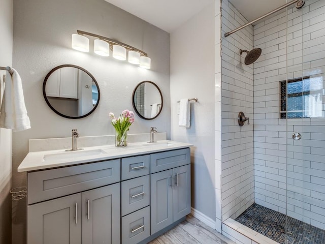 bathroom with double vanity, tiled shower, and a sink