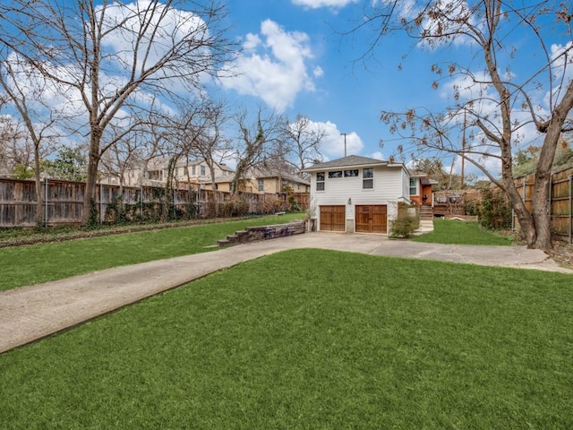 view of yard with driveway, an attached garage, and fence