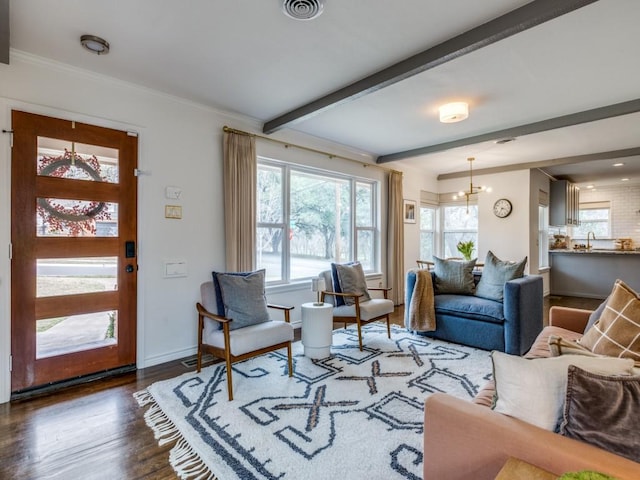 living room with beam ceiling, plenty of natural light, wood finished floors, and a chandelier