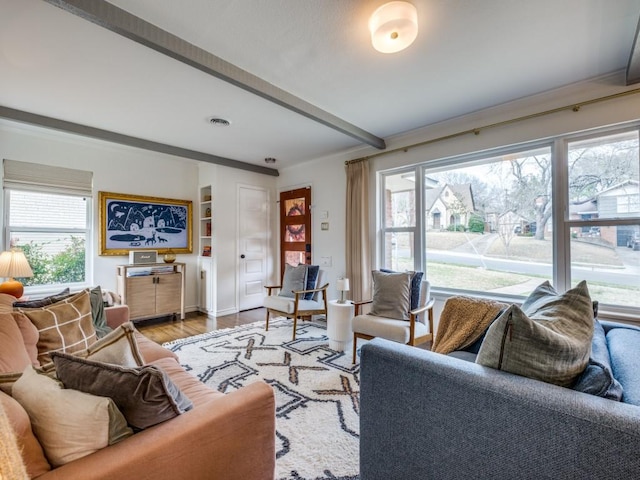 living area with a wealth of natural light, beamed ceiling, baseboards, and light wood-style flooring