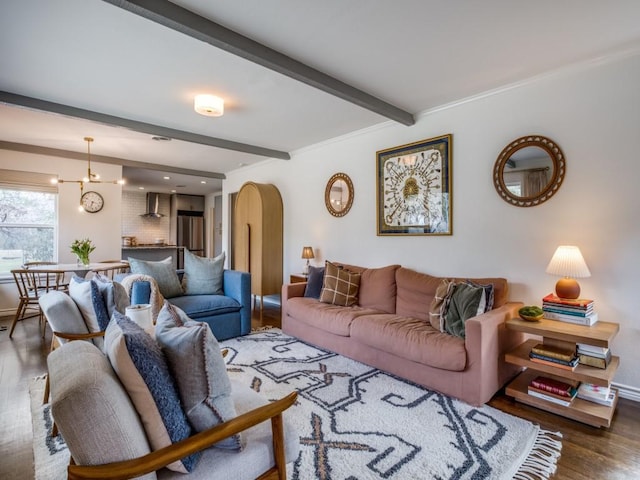 living area with arched walkways, beamed ceiling, an inviting chandelier, and wood finished floors