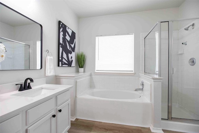 bathroom with vanity, a shower stall, a bath, and wood finished floors