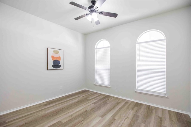 spare room featuring wood finished floors, baseboards, and ceiling fan