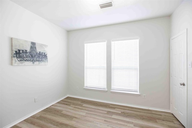 empty room featuring wood finished floors, visible vents, and baseboards