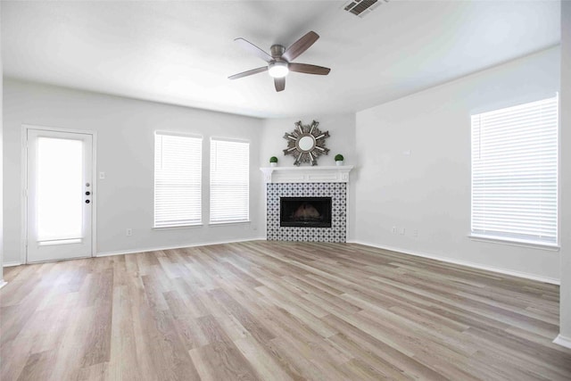 unfurnished living room with light wood-style floors, a fireplace, visible vents, and a wealth of natural light