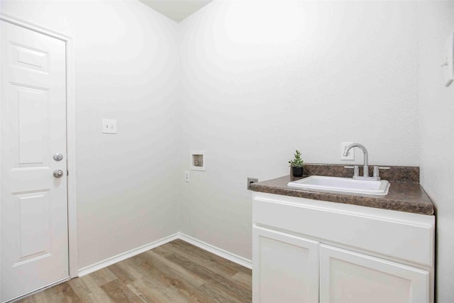 clothes washing area with light wood finished floors, baseboards, hookup for a washing machine, cabinet space, and a sink