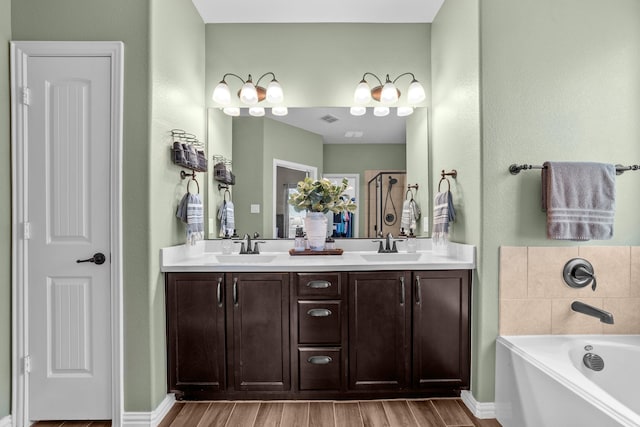 full bathroom featuring double vanity, a garden tub, wood finished floors, and a sink