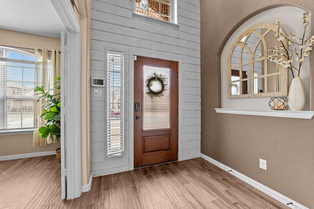 foyer entrance with baseboards and wood finish floors