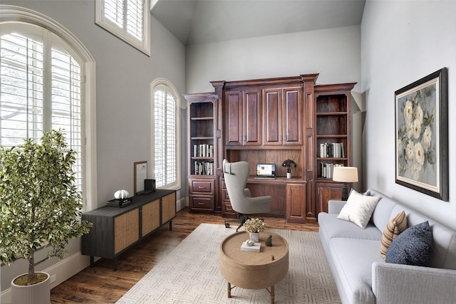 office space with dark wood-style floors, built in desk, high vaulted ceiling, and baseboards