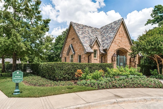 view of front facade with brick siding and a high end roof