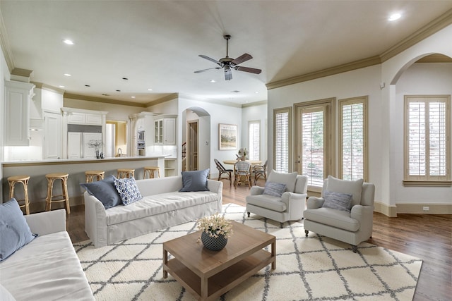 living area with recessed lighting, light wood-type flooring, arched walkways, and baseboards