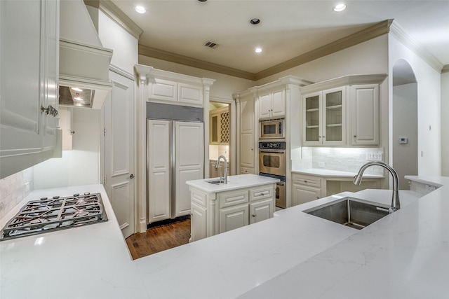 kitchen with a sink, built in appliances, ornamental molding, and light stone countertops