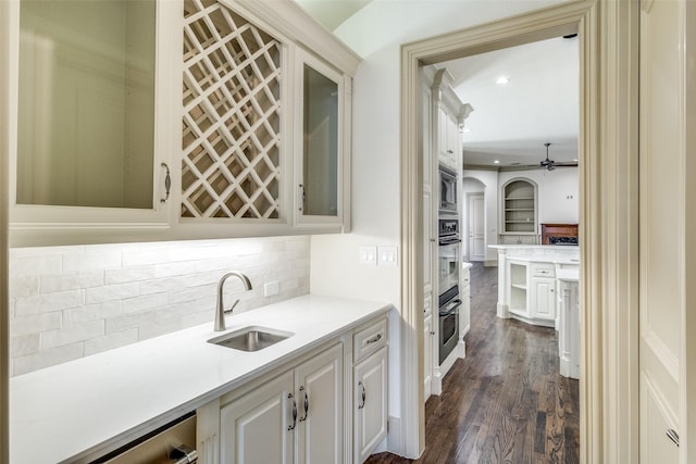 kitchen with a sink, glass insert cabinets, backsplash, and appliances with stainless steel finishes