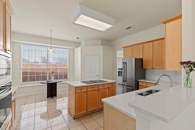 kitchen with a peninsula, a sink, appliances with stainless steel finishes, pendant lighting, and a center island