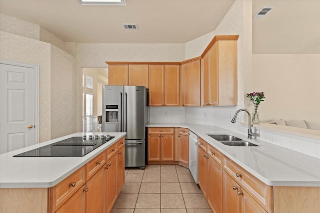 kitchen featuring visible vents, stainless steel fridge, black electric cooktop, and a sink