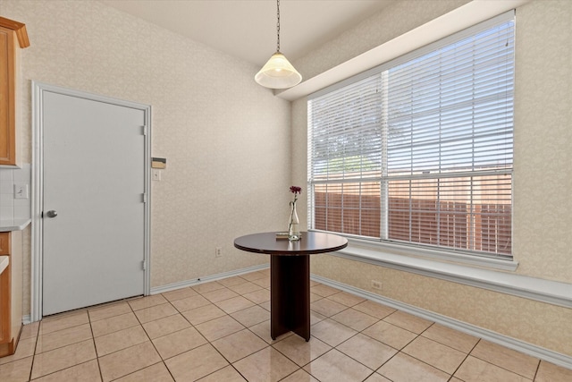 unfurnished dining area featuring light tile patterned floors, wallpapered walls, and baseboards