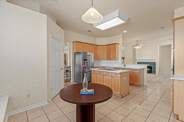 kitchen featuring stainless steel fridge, a peninsula, light brown cabinetry, and light countertops